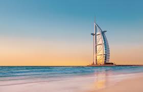 Burj Al Arab luxury hotel in Dubai at sunset with golden sky and calm beach